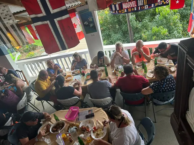 Guests sharing lunch on the restaurant terrace beneath flags left by visiting sailors