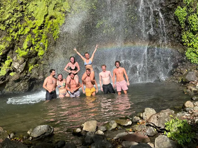 Tour group standing in a waterfall pool with a rainbow in the spray